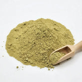 A close-up of vibrant green Herb & Honey 100% Pure Korean Bitter Melon Powder with a small wooden scoop on a white background.