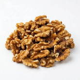 A pile of premium Herb & Honey California Walnut light halves and pieces on a white background.