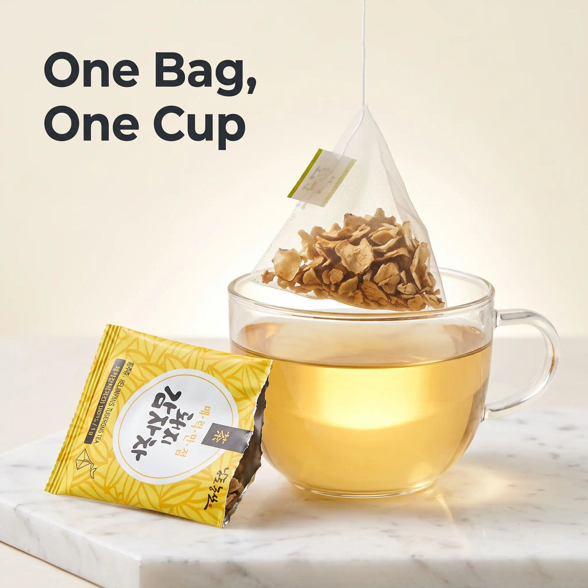 Close-up of a pyramid tea bag filled with dried Jerusalem artichoke chips steeping over a glass cup