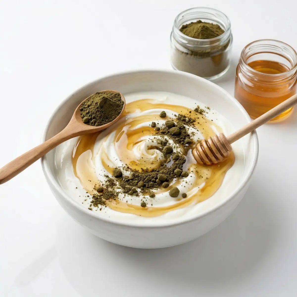 A white bowl of creamy yogurt topped with Herb & Honey Graviola Soursop Leaf Powder and a drizzle of honey, shown with a wooden spoon.