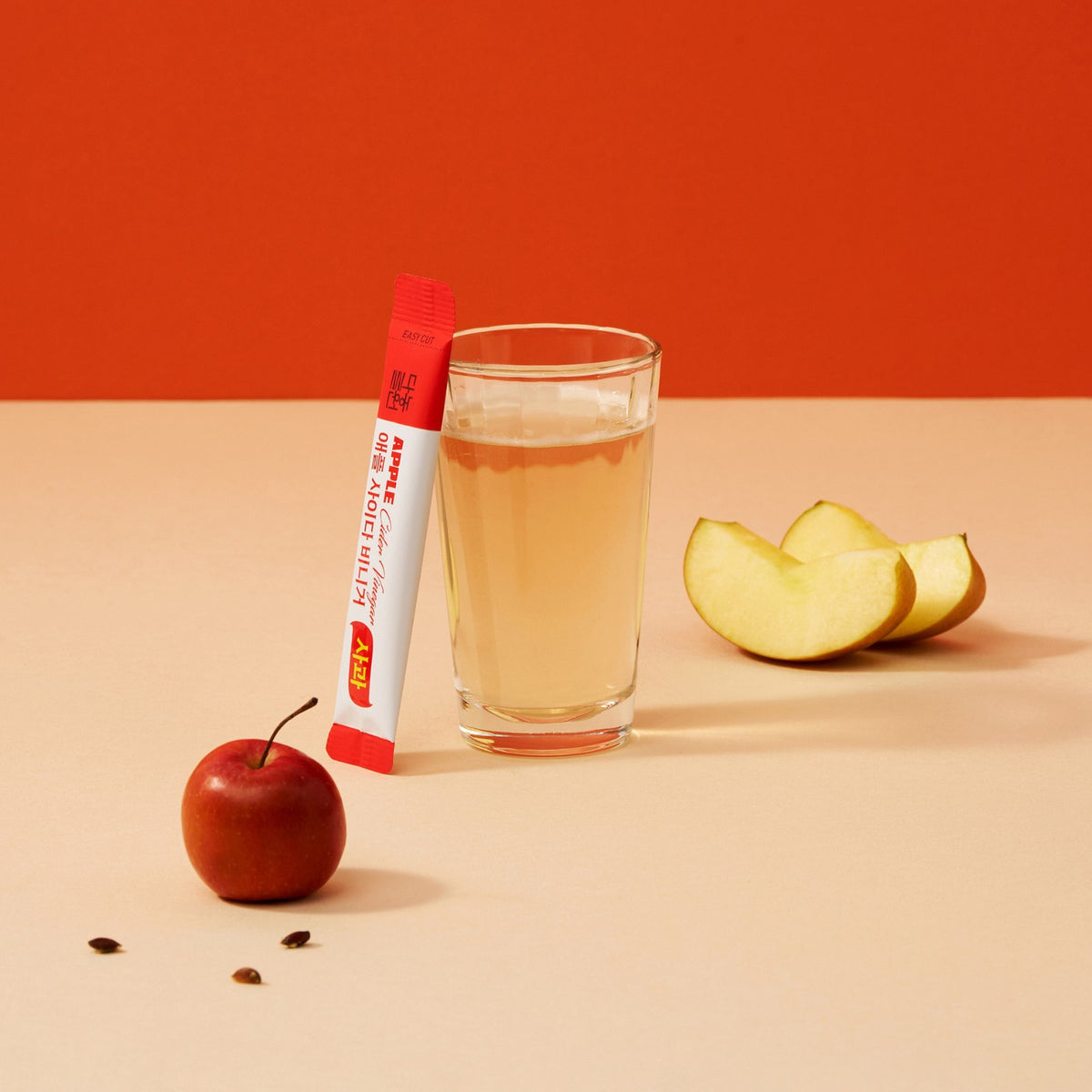 ACV Apple powder stick leaning on a glass of apple cider vinegar drink with apple slices