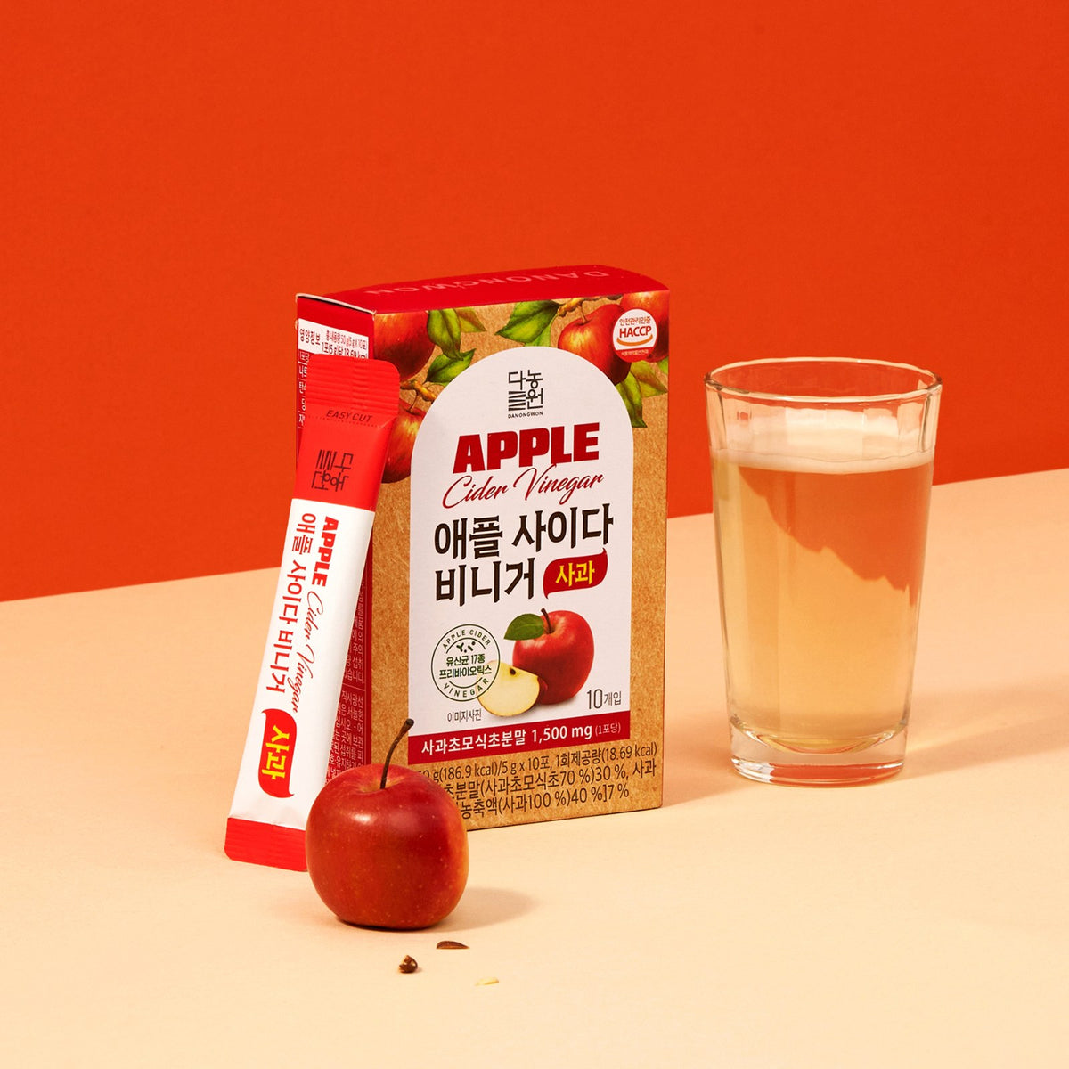 Danongwon ACV Apple box and 5 g stick next to a glass of apple cider vinegar drink