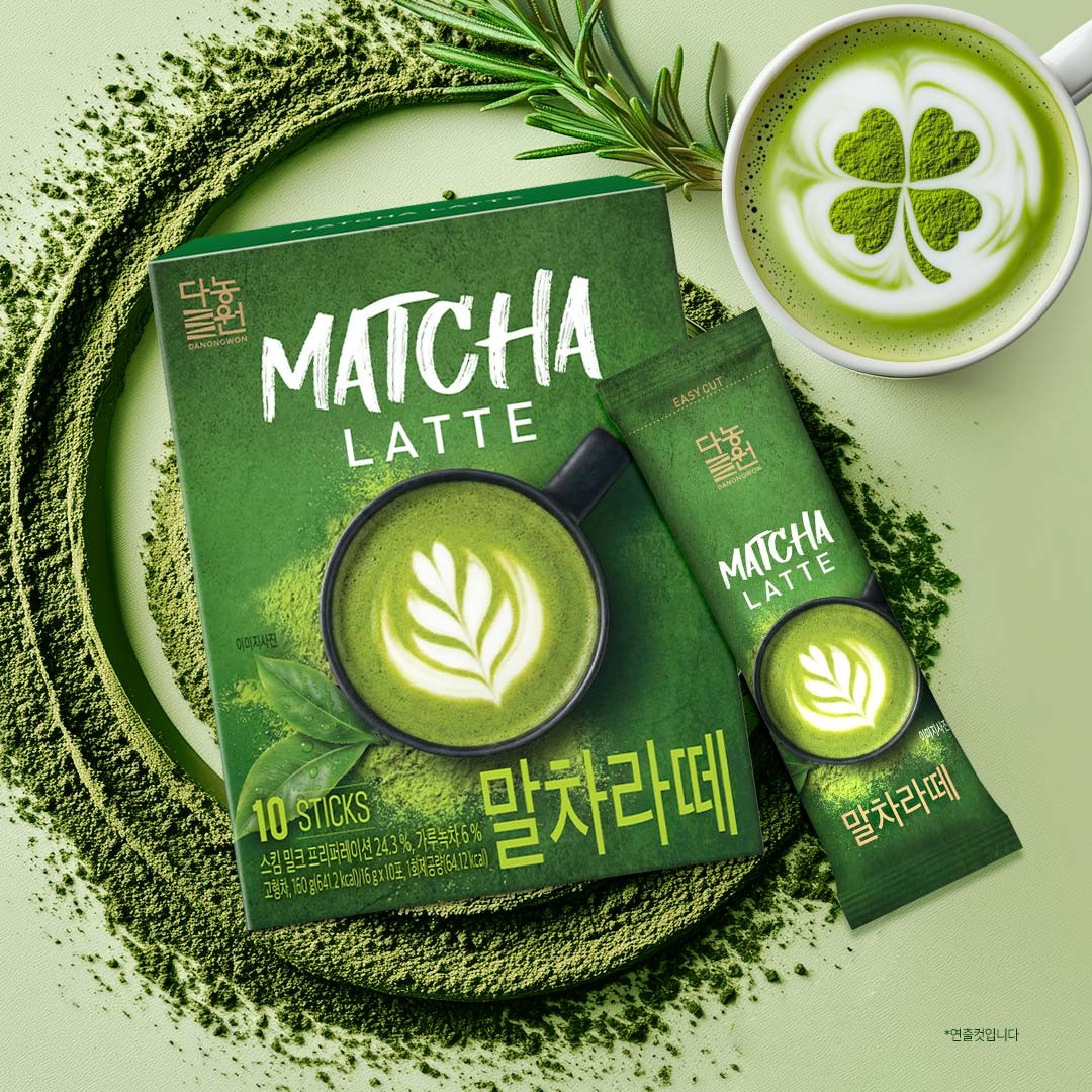 Korean matcha latte mix box and single stick beside a cup of matcha latte with clover latte art