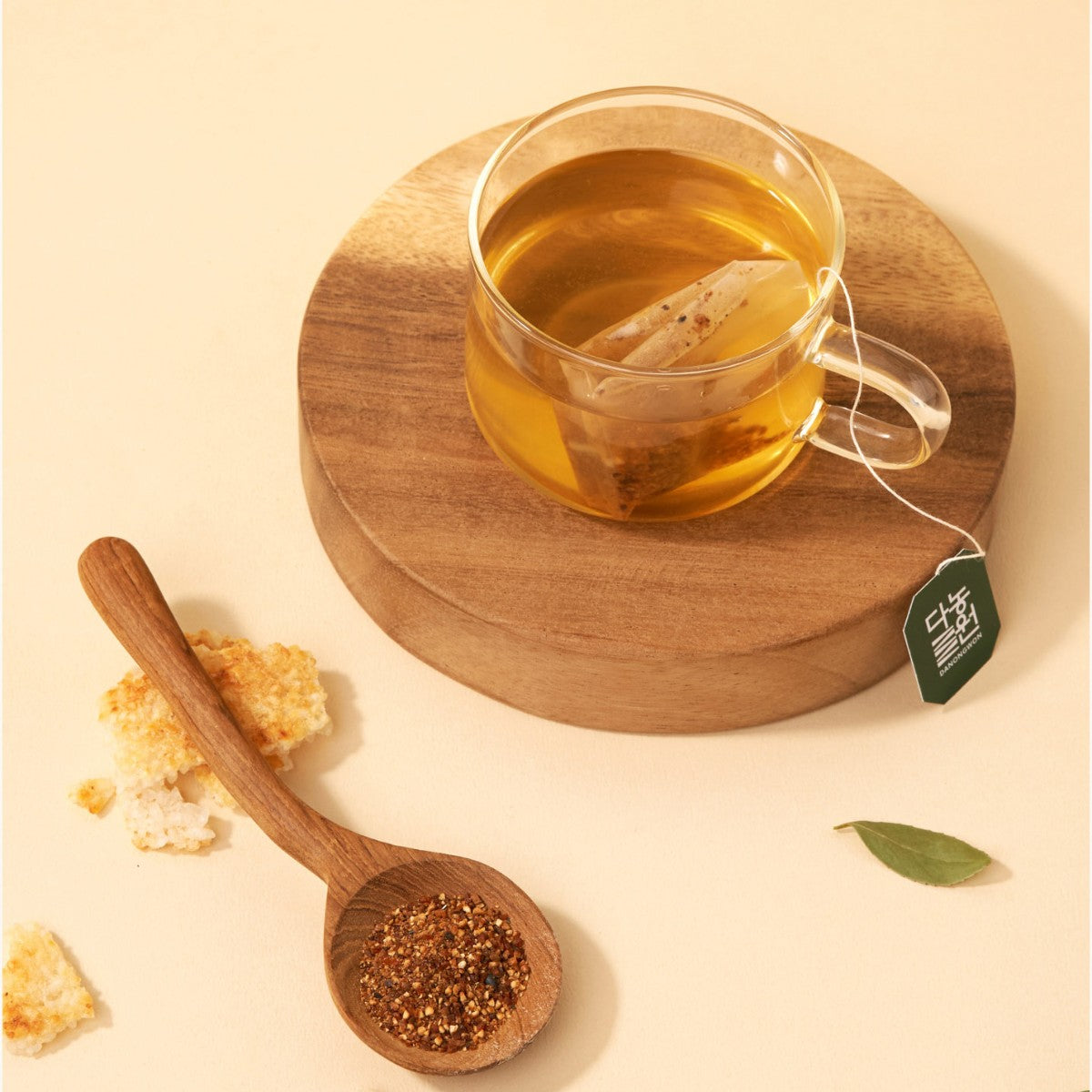 Glass cup of Korean nurungji Solomon's seal tea with a tea bag and a spoon of roasted tea blend
