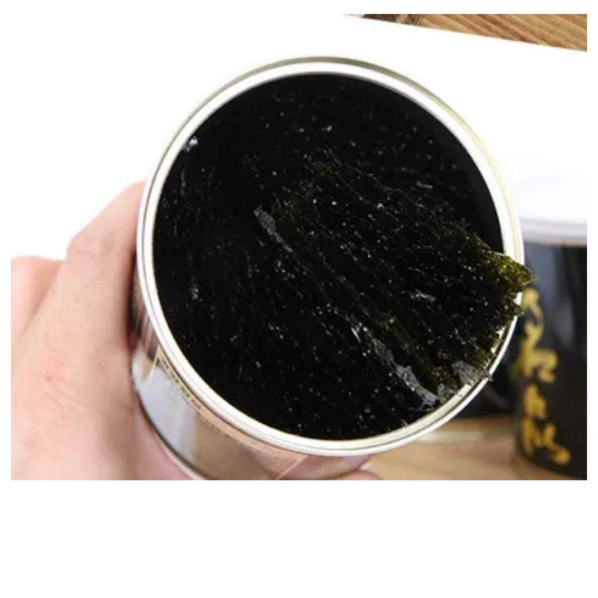 Korean roasted seasoned laver — open tin can held in hand showing the stacked gim sheets inside