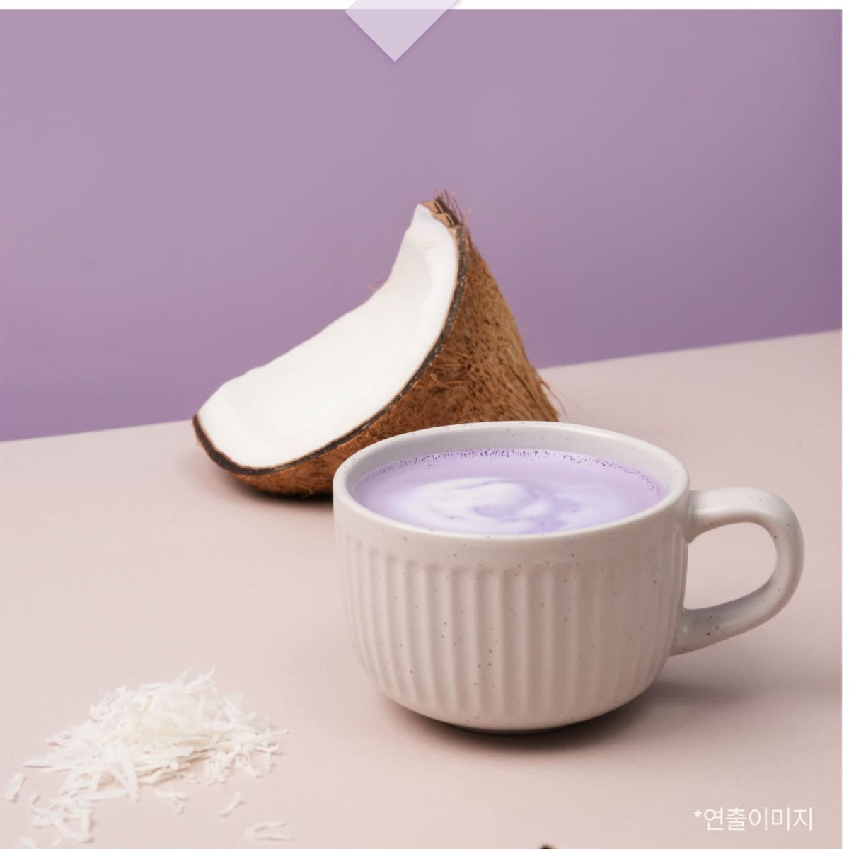 Hot Korean ube coconut latte in a white cup beside a halved coconut