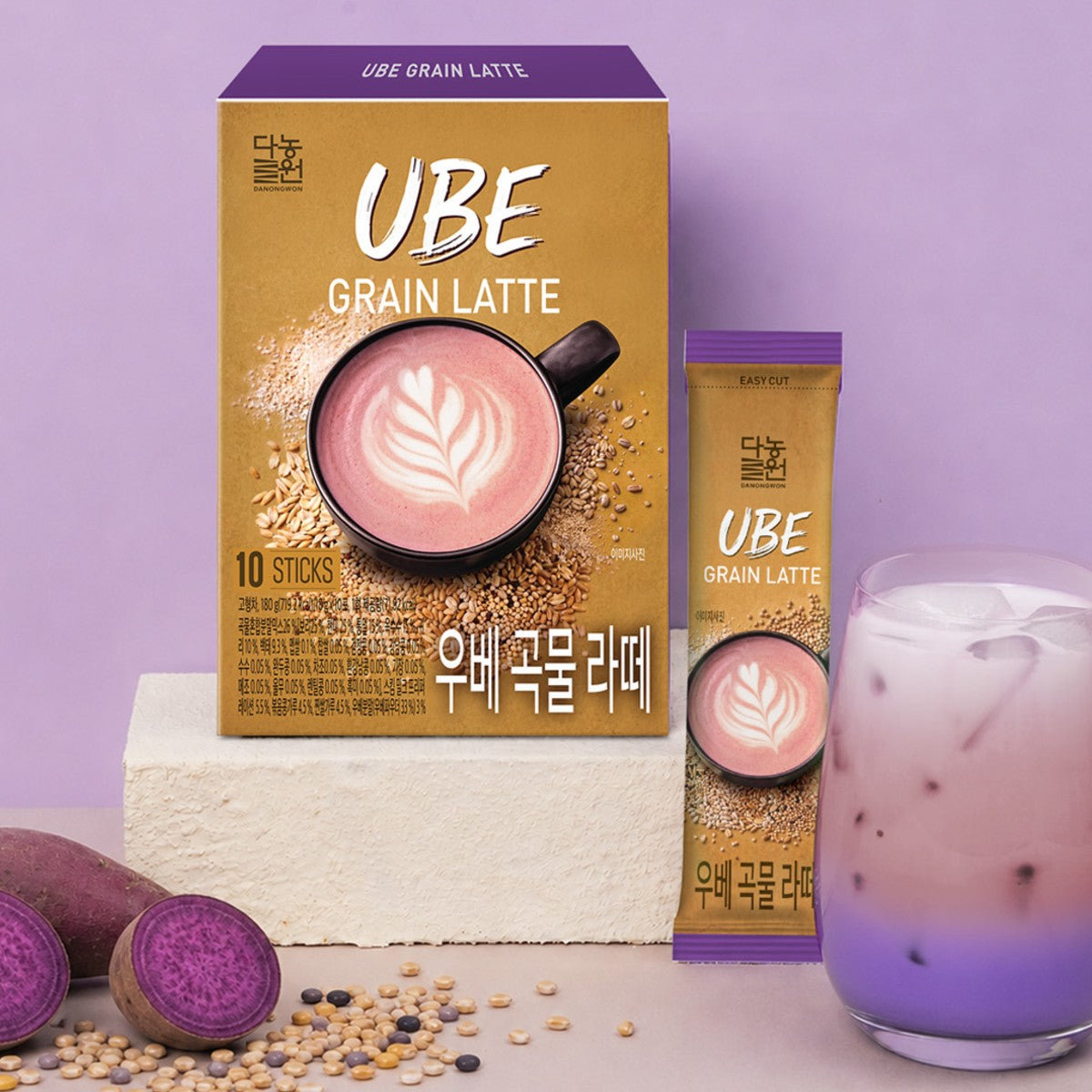 Korean ube grain latte box and stick beside an iced purple latte, halved ube and mixed grains