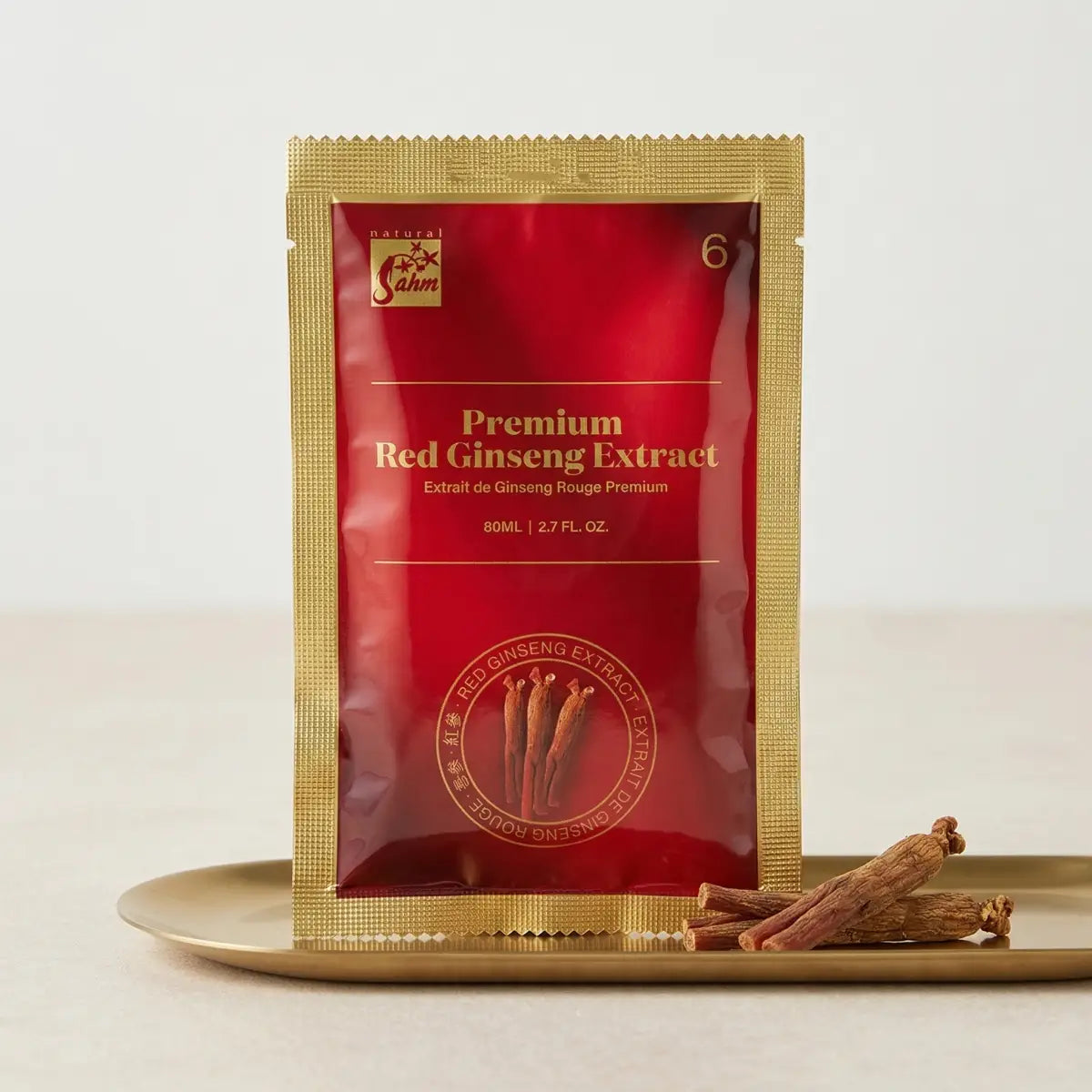 Single pouch of Sahm Canadian Premium Red Ginseng Extract with dried ginseng roots on a gold plate, 6-year-grown Ontario ginseng.